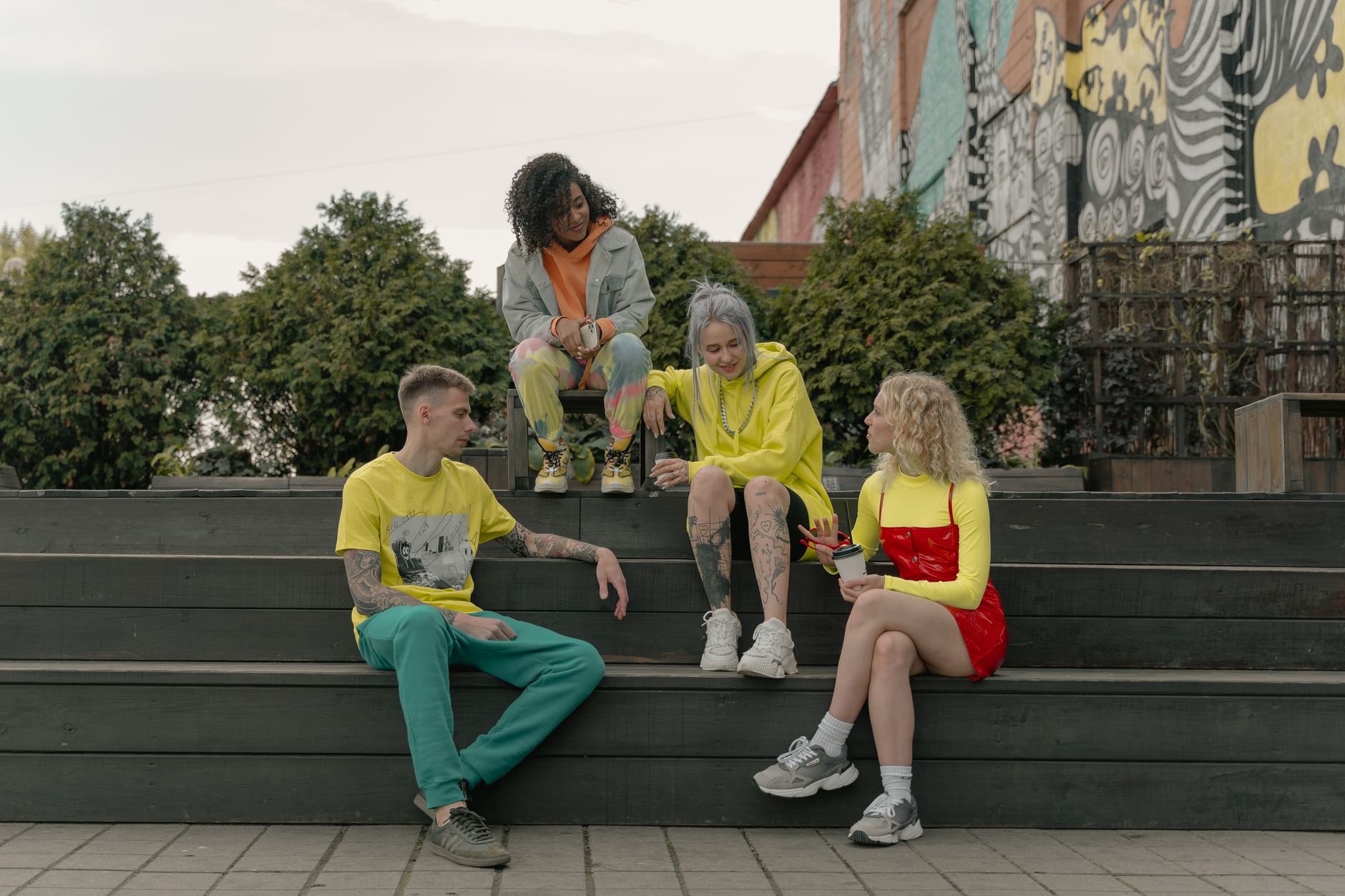 Group of young adults relaxing and chatting on steps in front of colorful street art. — A useful guide to choosing the ultima