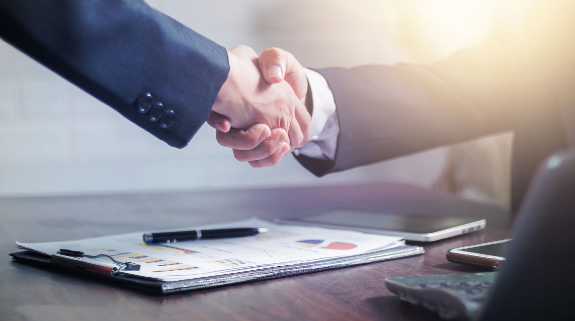 Professional handshake agreement over business charts in an office setting. — ABS Plastic Delivering Impact-Resistant Enginee