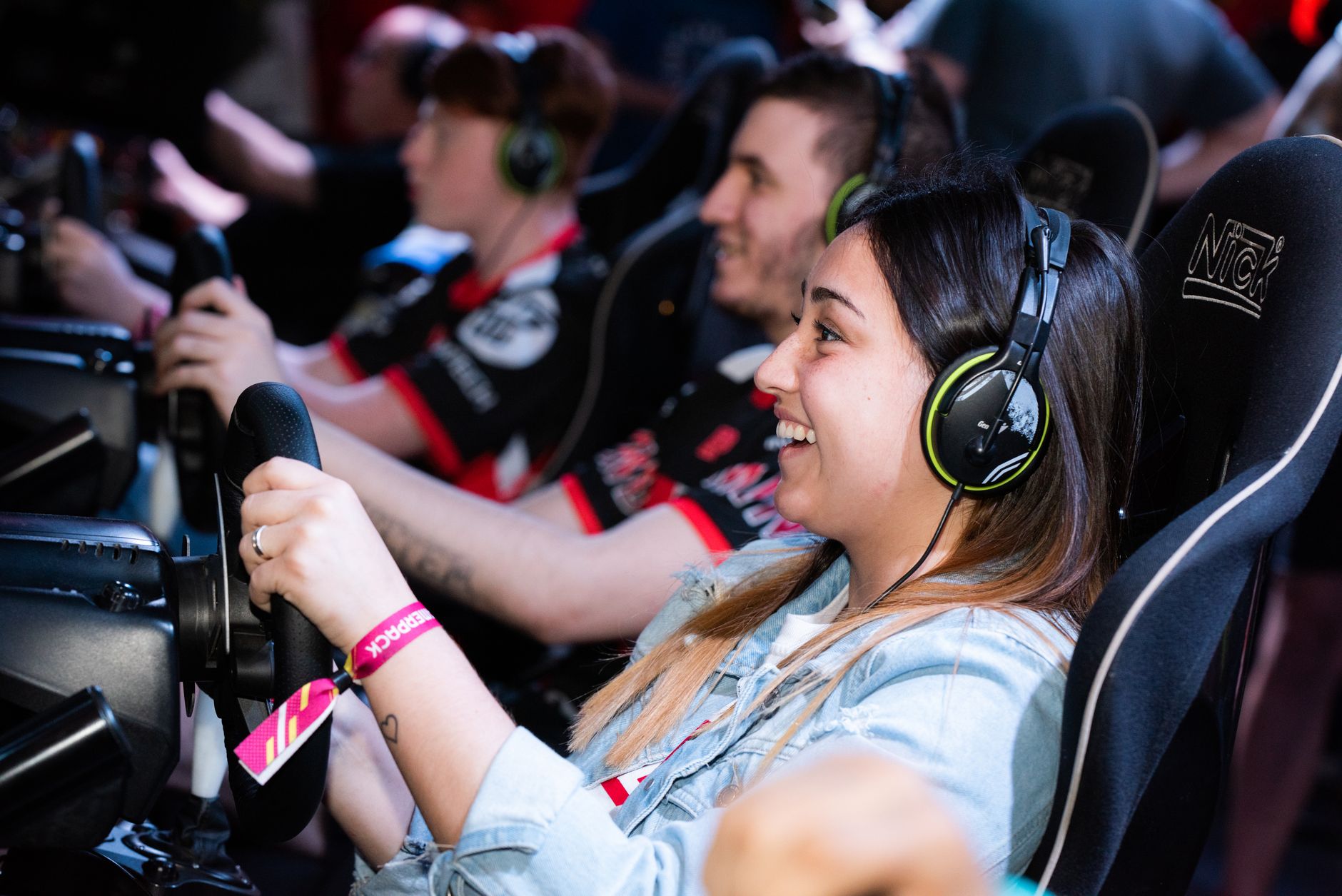 A group of people enjoying an immersive gaming experience at an e-sports center with headphones and steering wheels. — Get Re