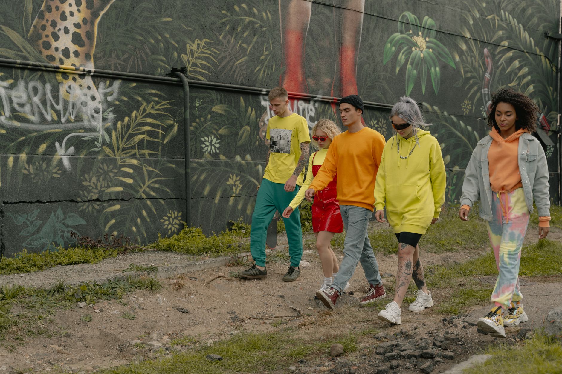 A group of trendy young adults walking by a vibrant urban mural, showcasing street style fashion. — Hairstyles For Old Men
