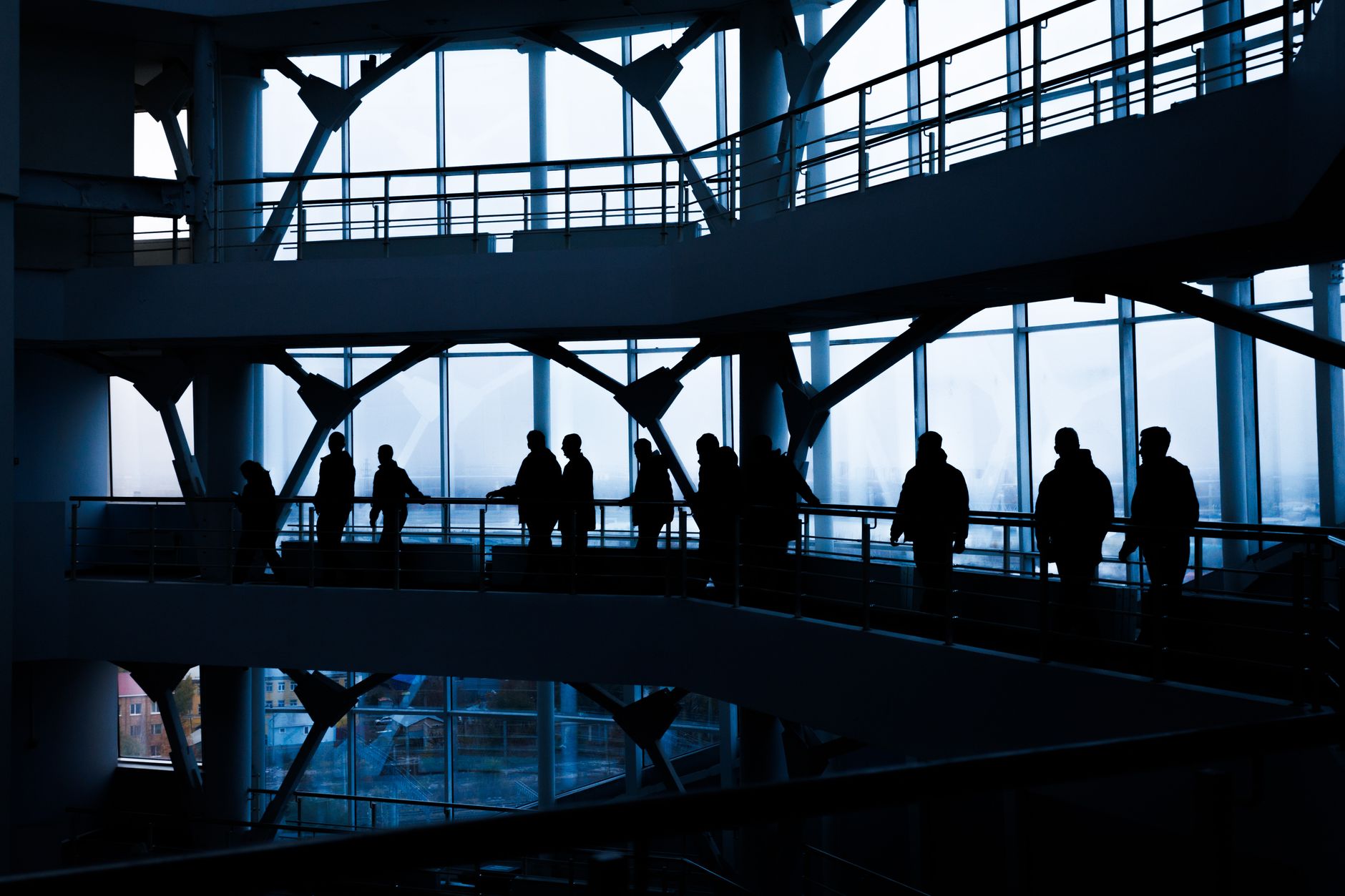 Silhouettes of people walking in a modern architectural building with large windows. — How MetaTrader 4 for macOS Combines Po