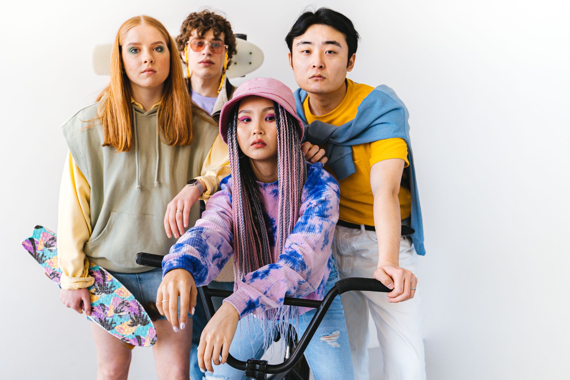 A trendy, diverse group of friends with unique fashion and hairstyles posing indoors with skateboards and a bike. — Styling T