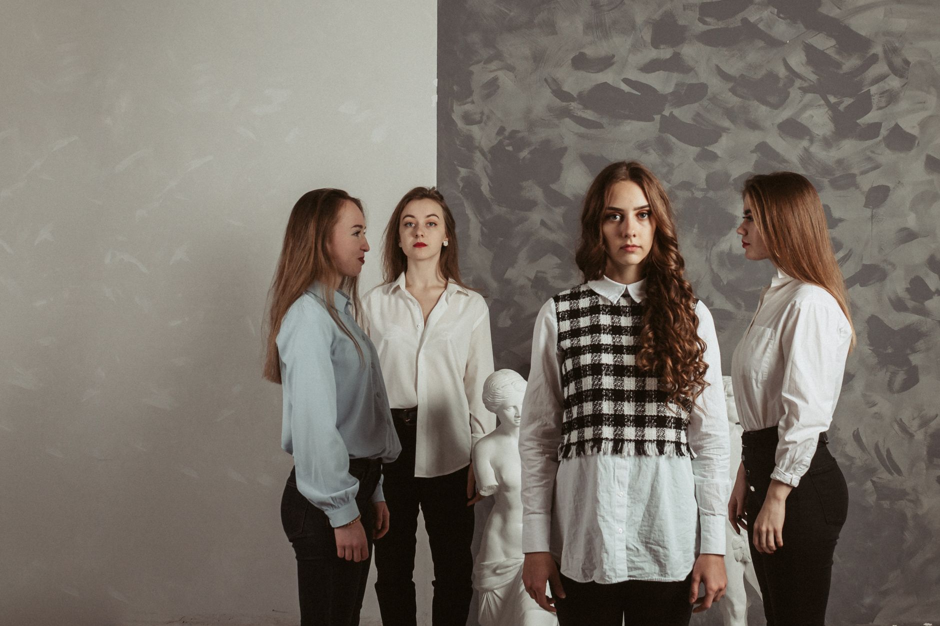 Stylish women in formalwear posing elegantly indoors with a classic sculpture backdrop. — Top Fashion: Virgins Saints and Ang