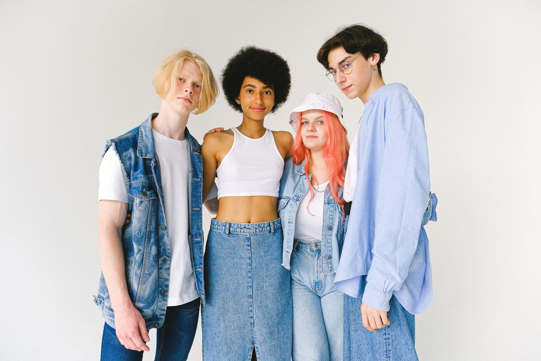 Content diverse teenager friends wearing denim clothes standing against white background hugging and looking at camera — Why
