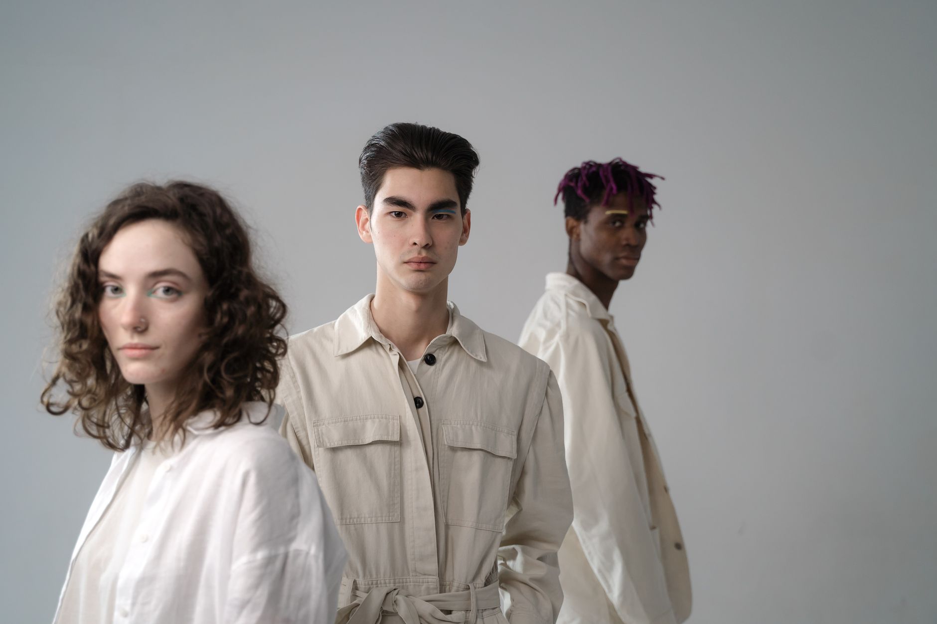 Group of diverse multiethnic young people wearing light beige and white cotton clothes standing in studio and looking at came